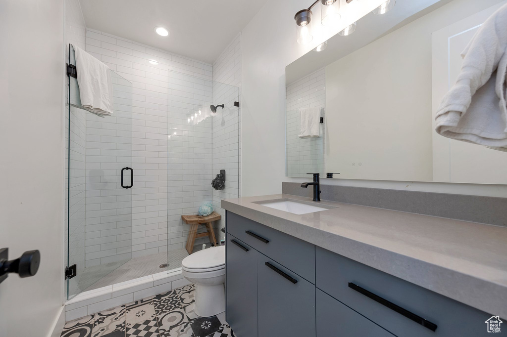 Bathroom with toilet, vanity, tile patterned flooring, and walk in shower