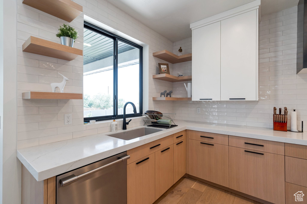 Kitchen with tasteful backsplash, sink, light wood-type flooring, light brown cabinetry, and dishwasher