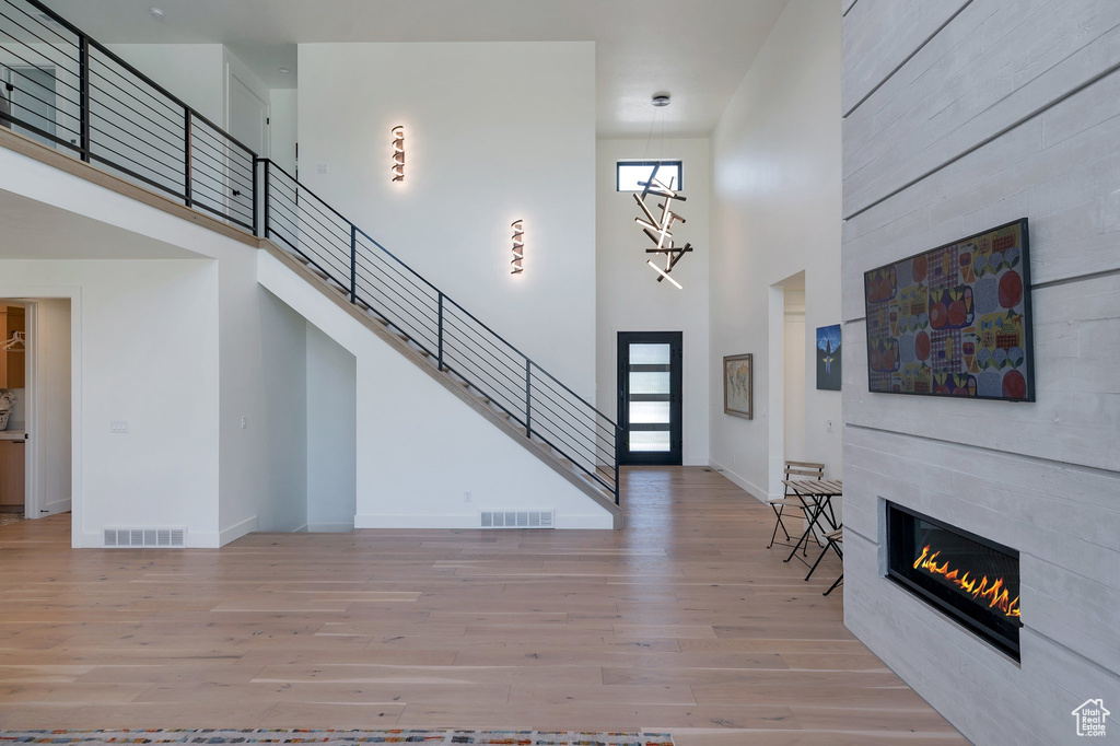 Foyer entrance with a fireplace, hardwood / wood-style floors, and a towering ceiling