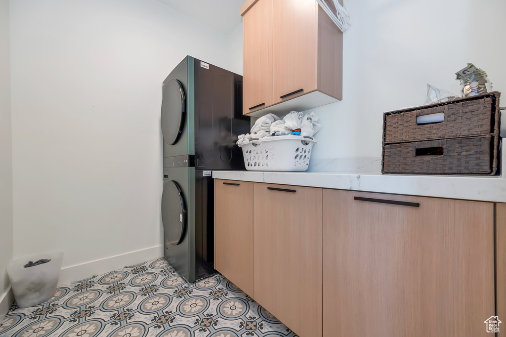 Kitchen featuring light brown cabinets, light tile patterned floors, and stacked washing maching and dryer