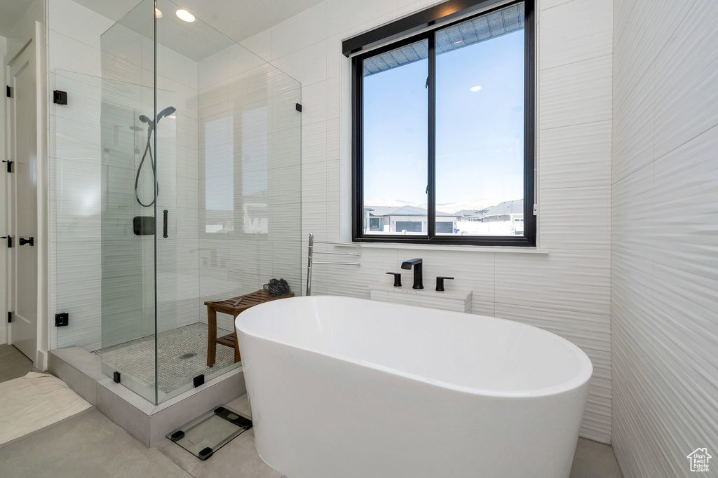 Bathroom with tile walls, shower with separate bathtub, and tile patterned floors