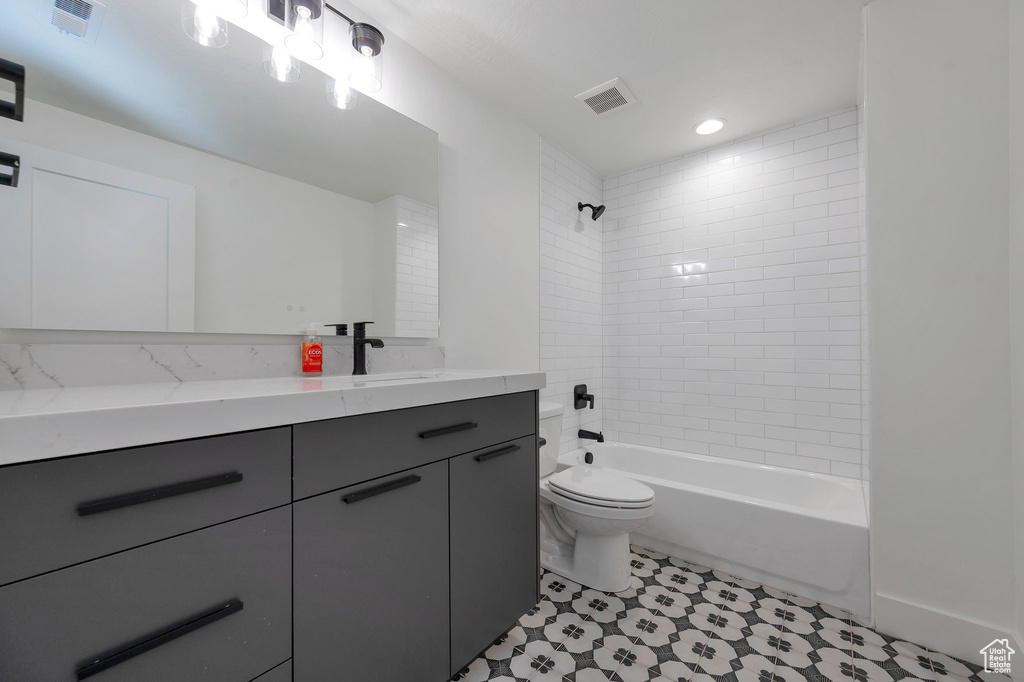 Full bathroom featuring vanity, tiled shower / bath, toilet, and tile patterned floors