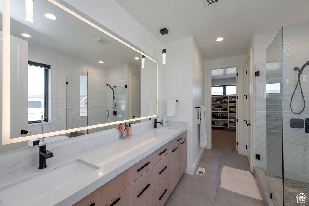 Bathroom featuring tile patterned flooring, walk in shower, and double vanity