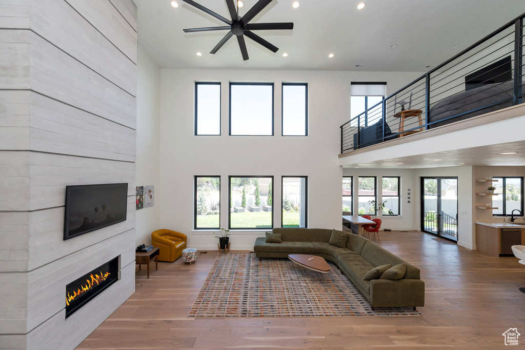 Living room with a fireplace, hardwood / wood-style flooring, a towering ceiling, and ceiling fan