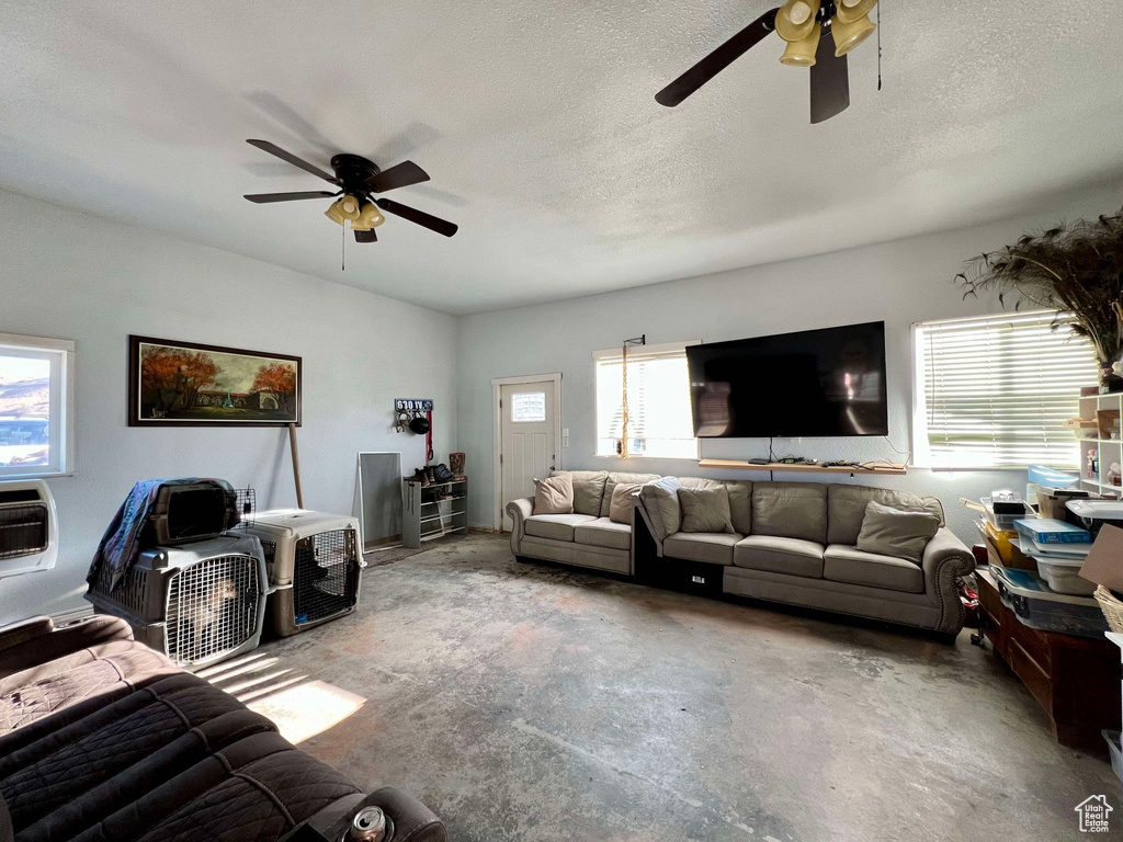 Living room with a textured ceiling, concrete flooring, a healthy amount of sunlight, and ceiling fan