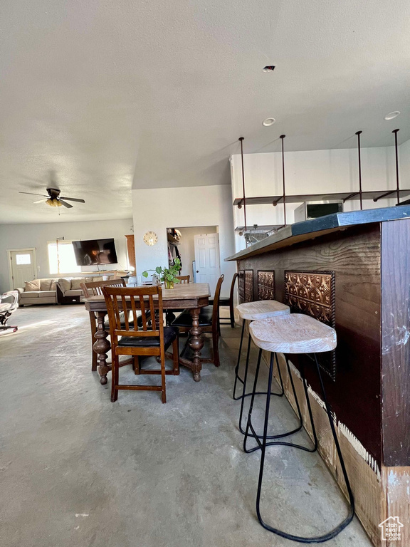 Dining room featuring concrete flooring, ceiling fan, and a textured ceiling
