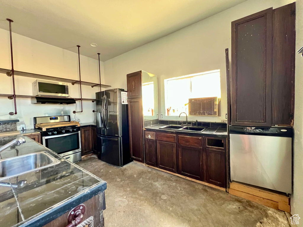 Kitchen featuring stainless steel appliances, dark brown cabinetry, and sink