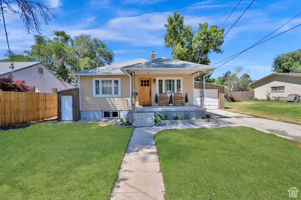 Bungalow-style home featuring a garage, an outbuilding, and a front yard