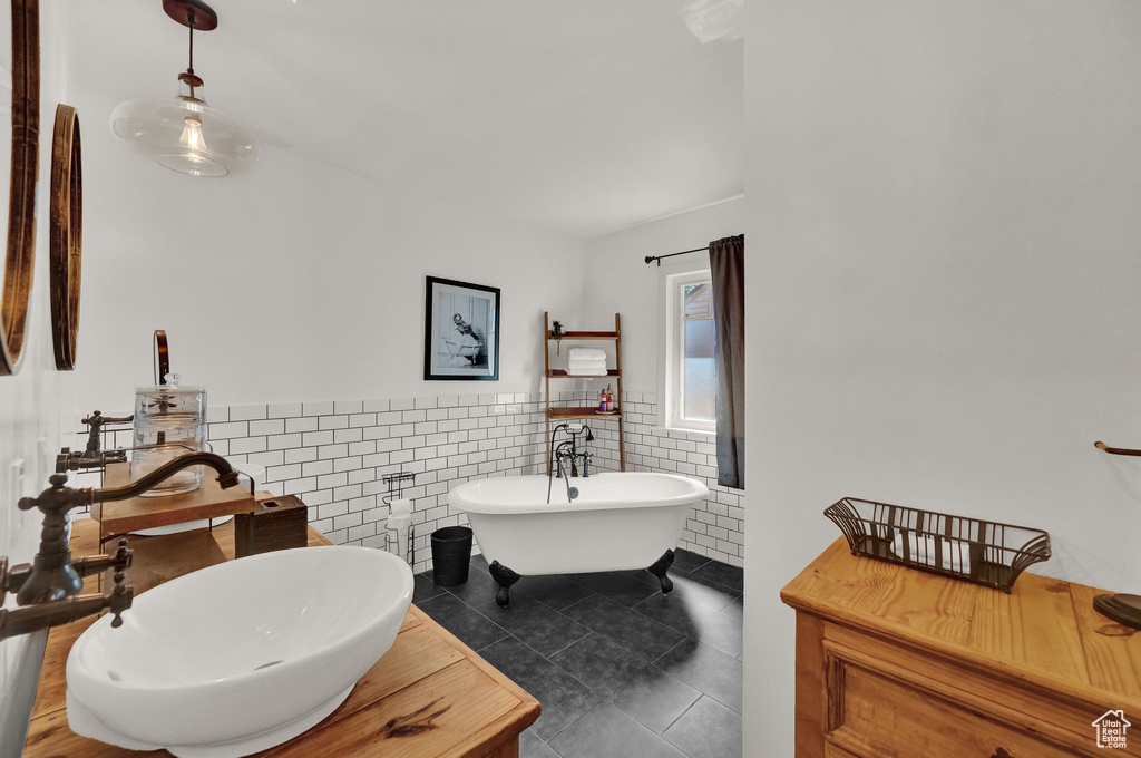 Bathroom with tile walls, tile patterned floors, sink, and a bathtub