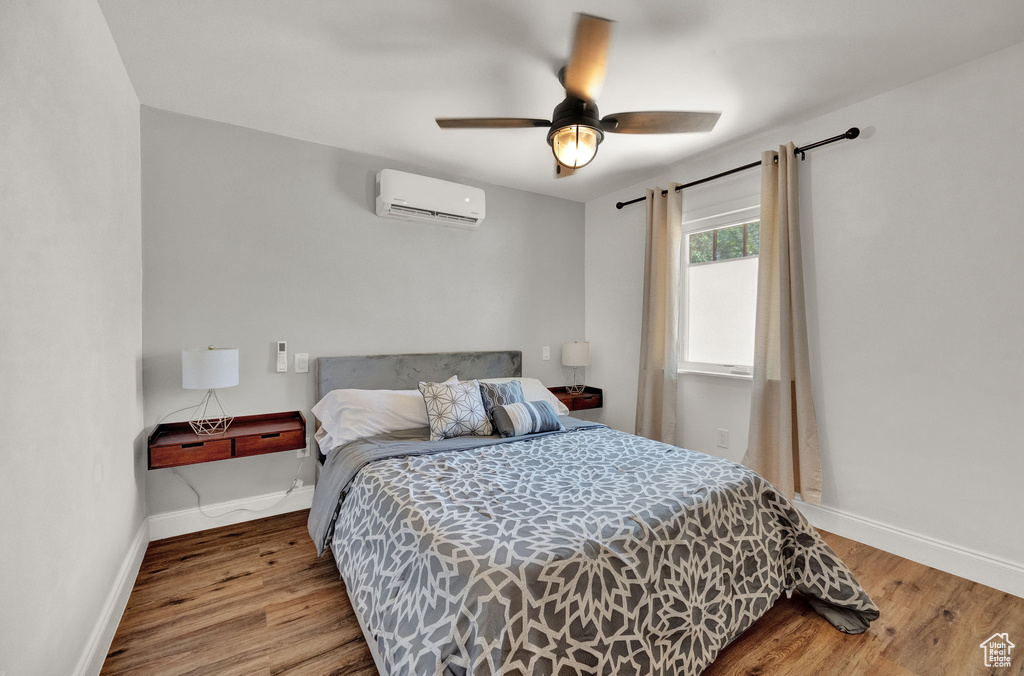 Bedroom with hardwood / wood-style flooring, a wall mounted AC, and ceiling fan