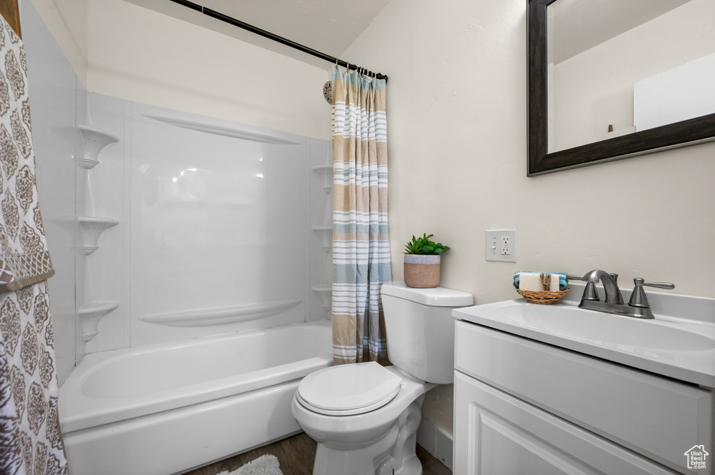 Full bathroom with shower / bath combo with shower curtain, toilet, vanity, and hardwood / wood-style floors