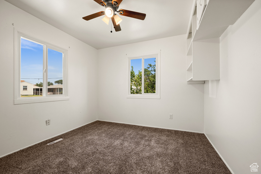 Carpeted spare room featuring a healthy amount of sunlight and ceiling fan