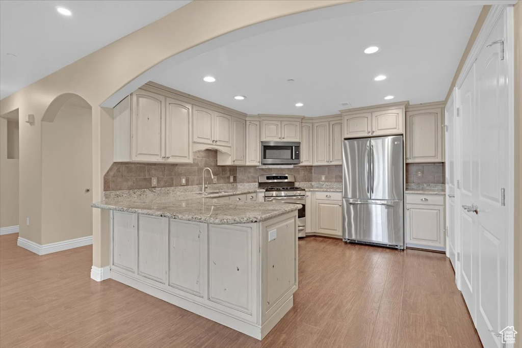 Kitchen featuring sink, tasteful backsplash, stainless steel appliances, and hardwood / wood-style floors