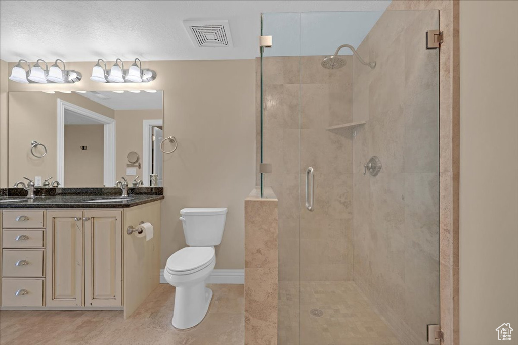 Bathroom with a shower with door, tile patterned flooring, a textured ceiling, toilet, and vanity