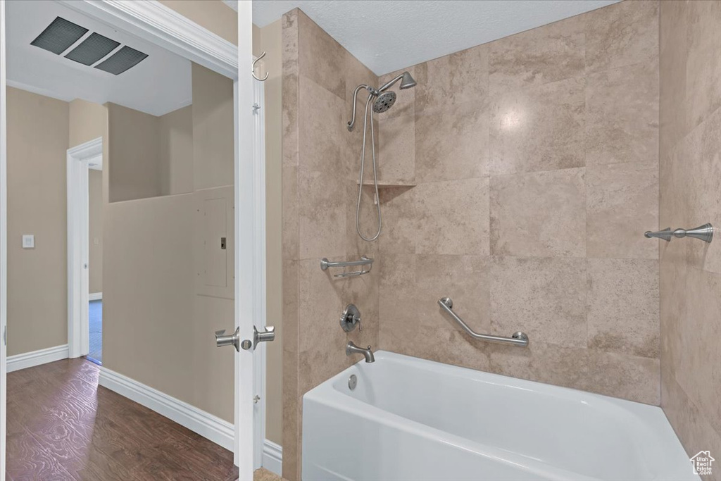 Bathroom featuring tiled shower / bath combo, a textured ceiling, and hardwood / wood-style floors