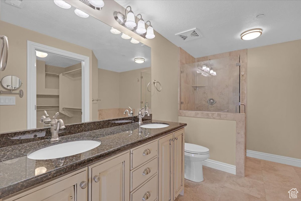 Bathroom featuring toilet, tile patterned flooring, walk in shower, and double vanity