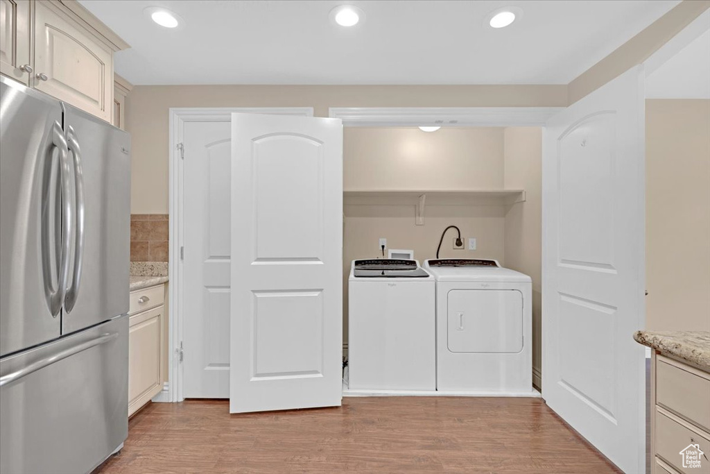 Washroom with separate washer and dryer and light hardwood / wood-style floors