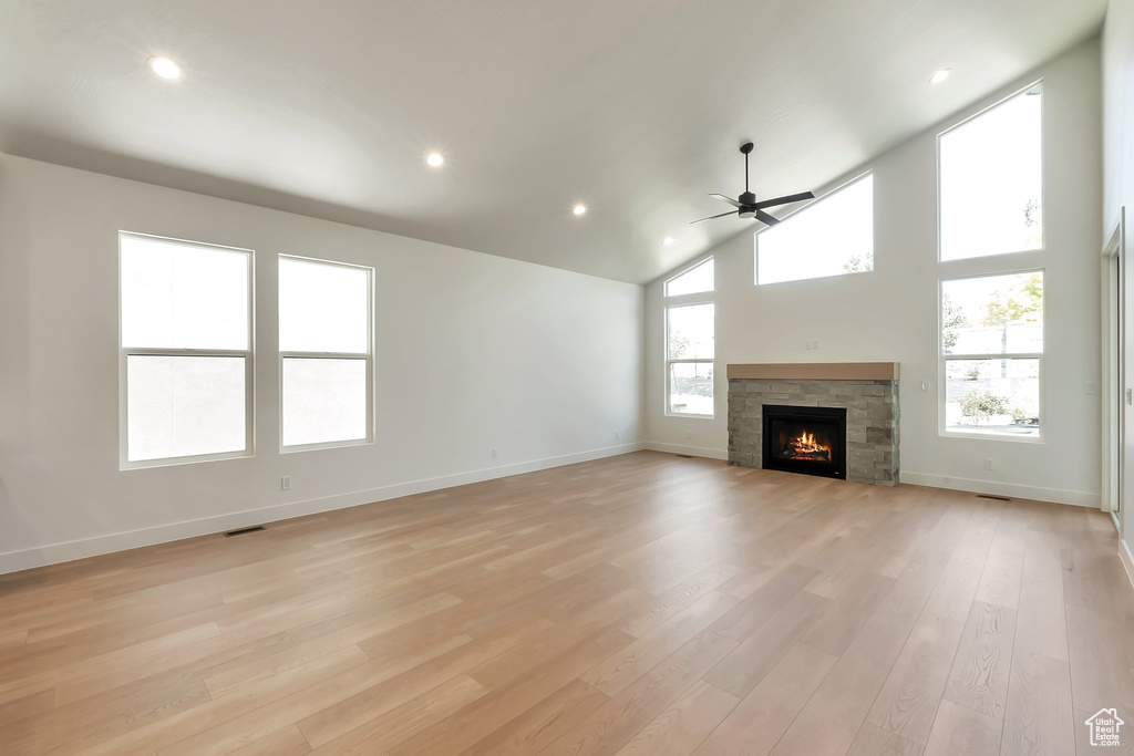 Unfurnished living room with light hardwood / wood-style flooring, a fireplace, lofted ceiling, and ceiling fan