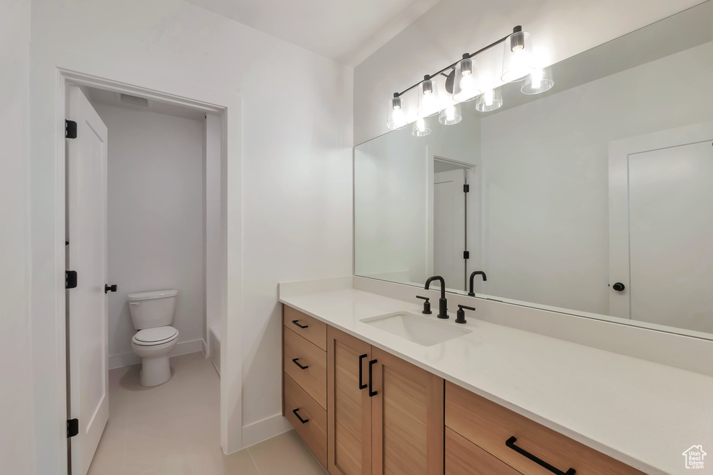 Bathroom with vanity, toilet, and tile patterned floors