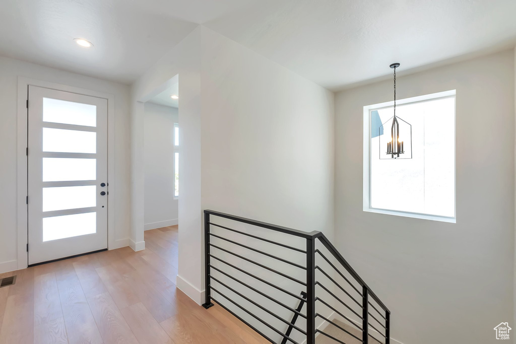 Interior space with a wealth of natural light, light wood-type flooring, and an inviting chandelier