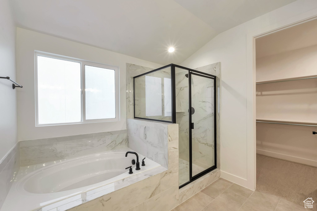 Bathroom featuring plenty of natural light, shower with separate bathtub, tile patterned floors, and vaulted ceiling