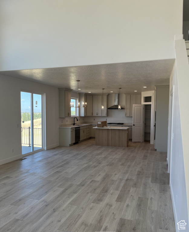 Kitchen featuring light wood-type flooring, a center island, gray cabinetry, wall chimney exhaust hood, and hanging light fixtures