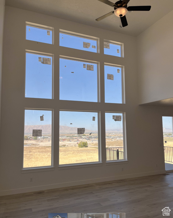 Unfurnished living room featuring a healthy amount of sunlight, ceiling fan, and hardwood / wood-style floors