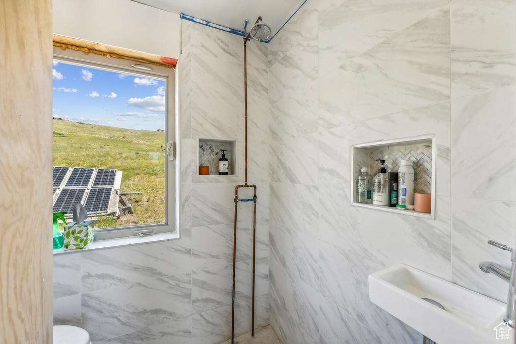 Bathroom featuring tile walls, toilet, and sink