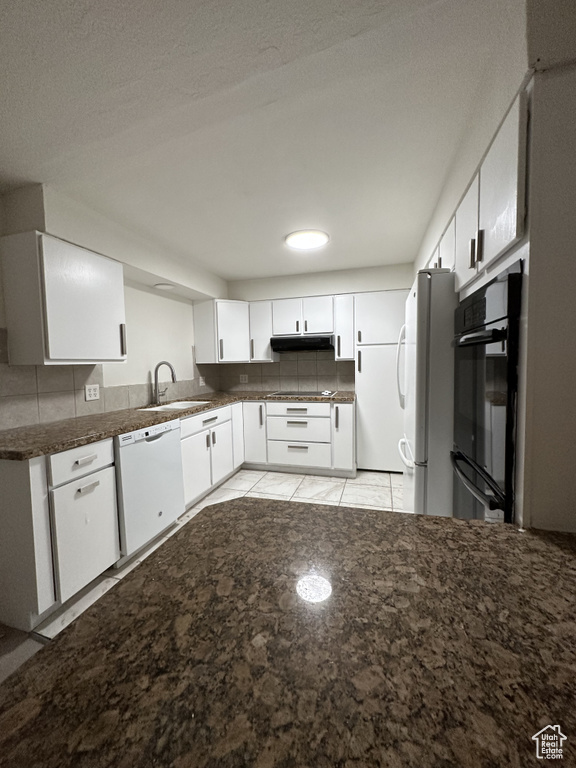 Kitchen with white cabinetry, black appliances, sink, light tile patterned floors, and backsplash