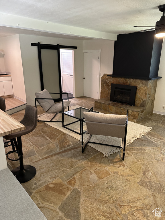 Living room with a stone fireplace and ceiling fan