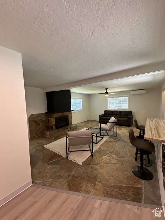 Living room featuring plenty of natural light, a fireplace, a textured ceiling, and hardwood / wood-style flooring