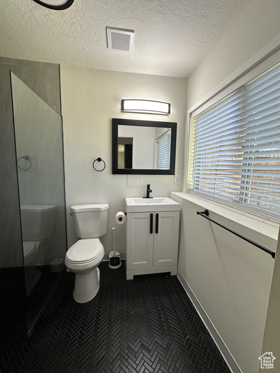 Bathroom with tile patterned flooring, toilet, vanity, and a textured ceiling