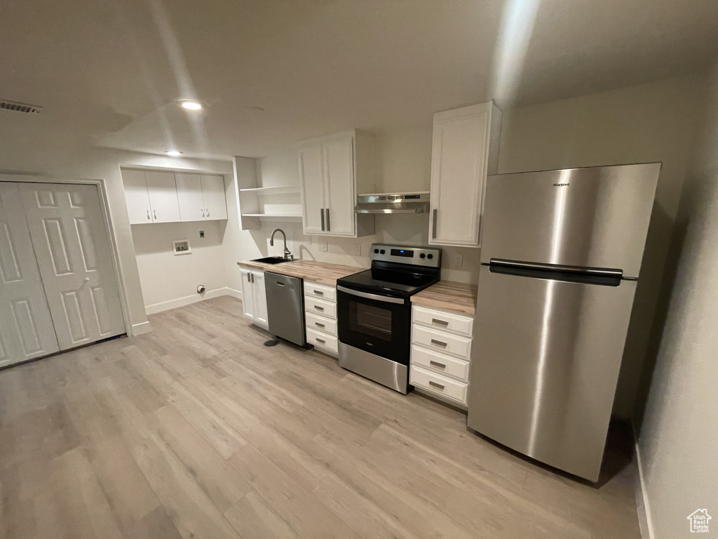 Kitchen featuring light hardwood / wood-style flooring, white cabinetry, butcher block countertops, and stainless steel appliances