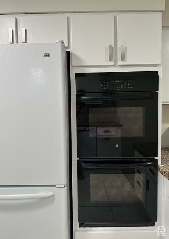 Interior details featuring black double oven, white fridge, and white cabinets