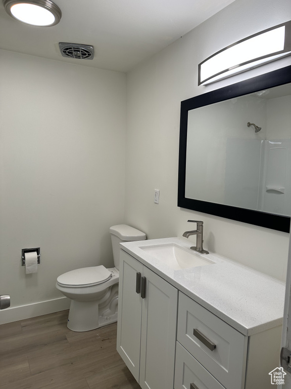 Bathroom featuring vanity, hardwood / wood-style flooring, and toilet