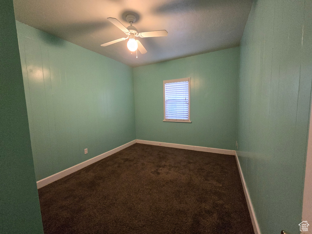 Empty room with dark colored carpet and ceiling fan