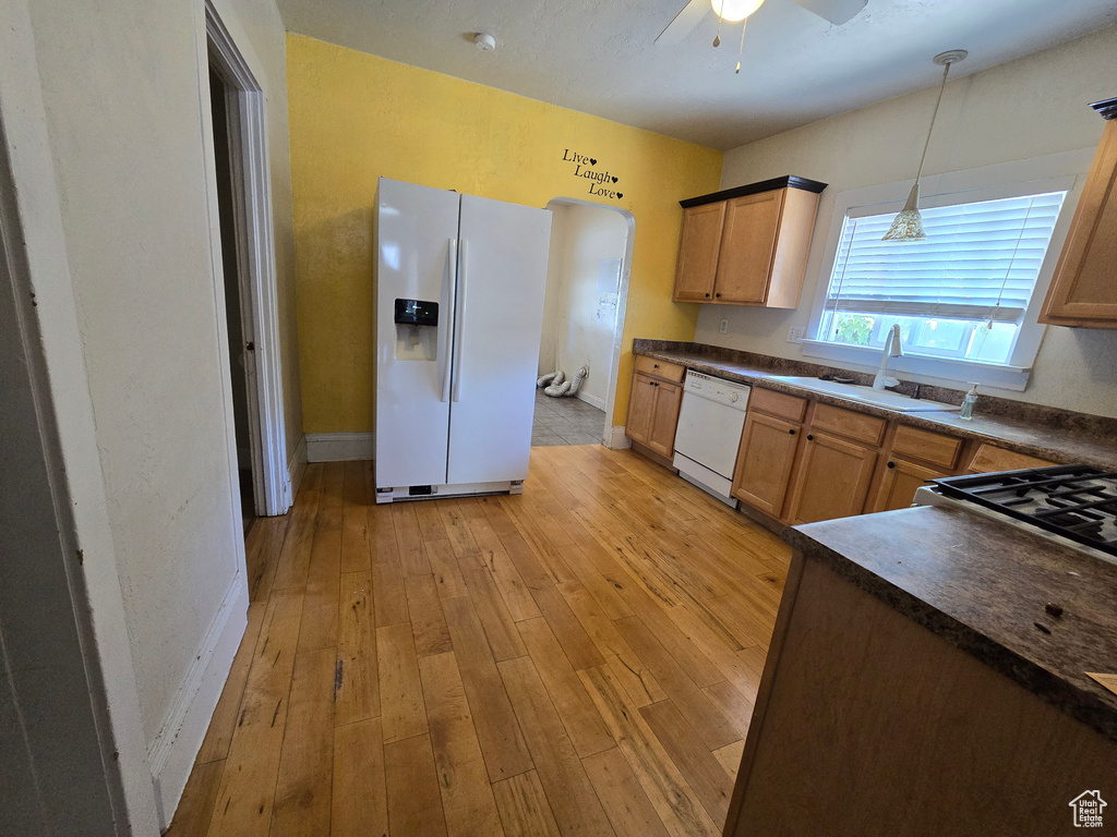 Kitchen with white appliances, ceiling fan, light hardwood / wood-style floors, pendant lighting, and sink