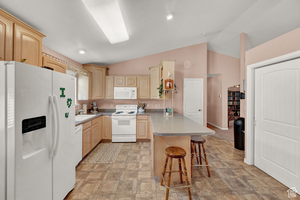 Kitchen with a kitchen breakfast bar, vaulted ceiling, white appliances, and light brown cabinetry