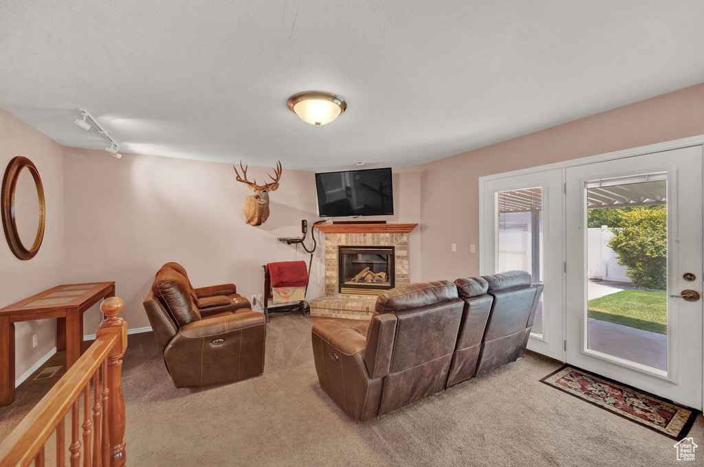 Living room with carpet flooring, a fireplace, rail lighting, and french doors