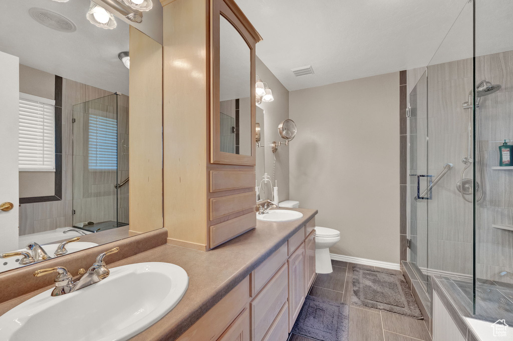 Bathroom featuring tile patterned flooring, toilet, and double sink vanity