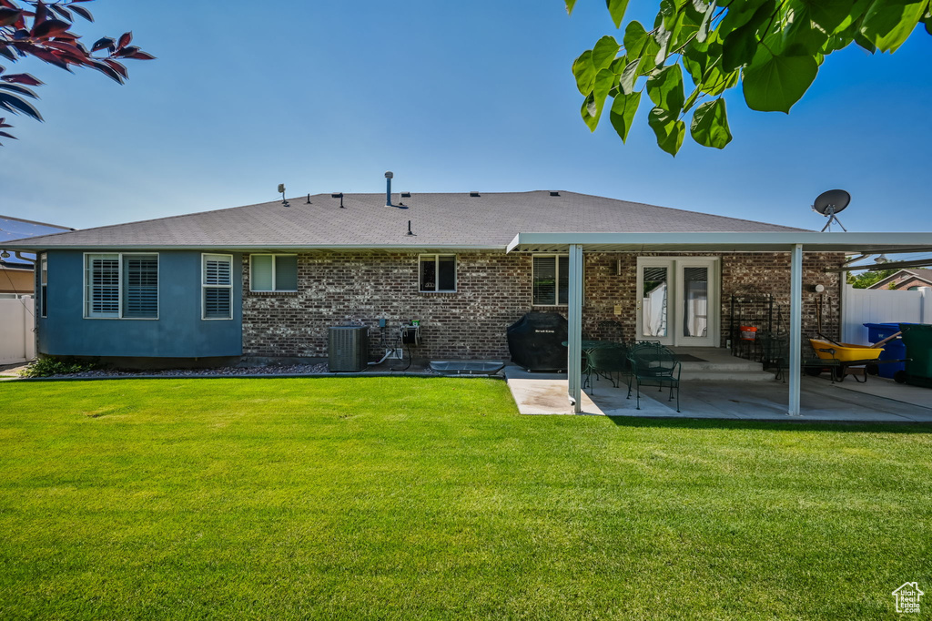 Rear view of house with a patio, a lawn, and central AC unit