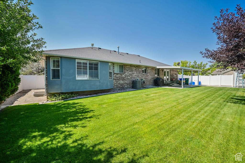 Back of property featuring a patio, central air condition unit, and a yard