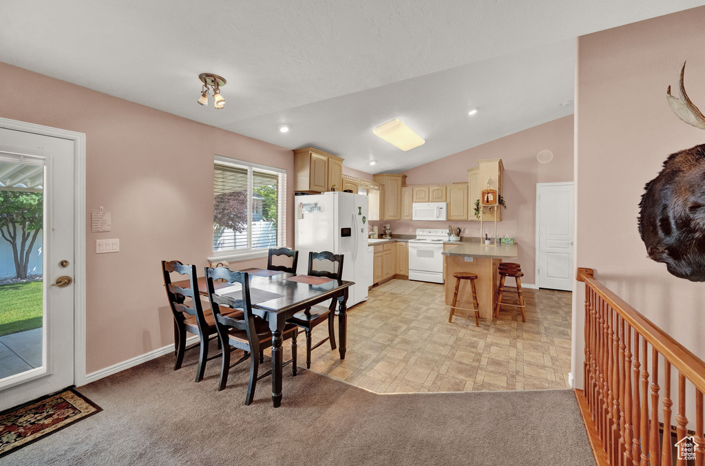 Carpeted dining space with lofted ceiling