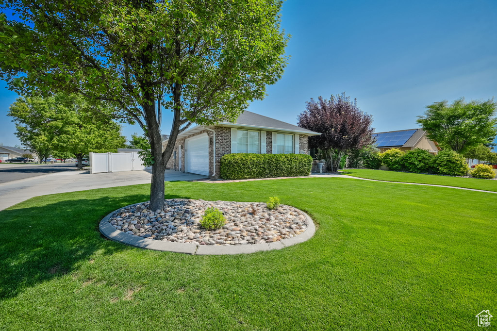 Ranch-style house with a garage, solar panels, and a front yard