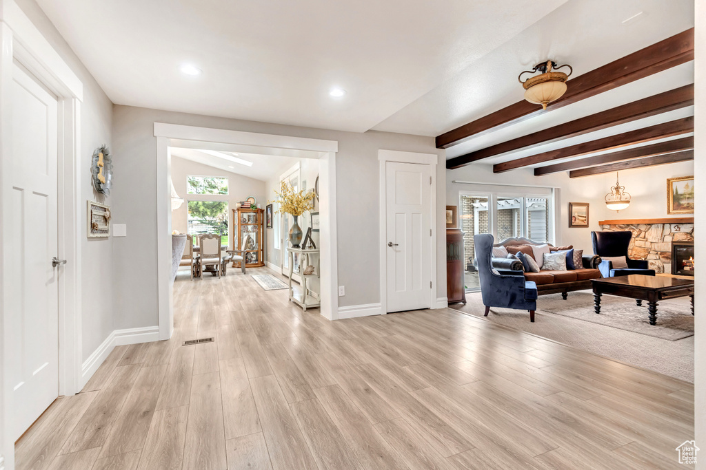 Hallway with lofted ceiling with beams and light hardwood / wood-style flooring