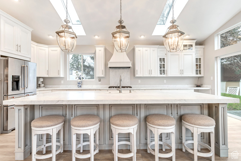 Kitchen with appliances with stainless steel finishes, white cabinets, and a large island with sink