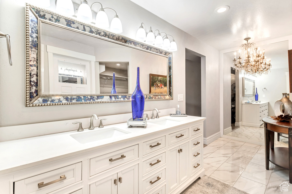 Bathroom featuring an inviting chandelier, dual bowl vanity, and tile patterned floors