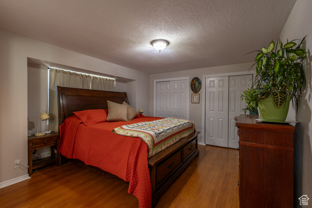 Bedroom featuring two closets, a textured ceiling, and hardwood / wood-style floors