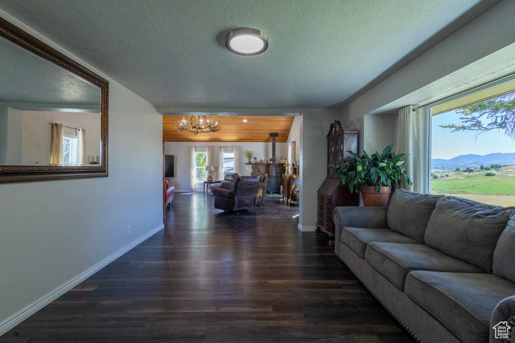 Living room with an inviting chandelier, dark wood-type flooring, a mountain view, and a textured ceiling