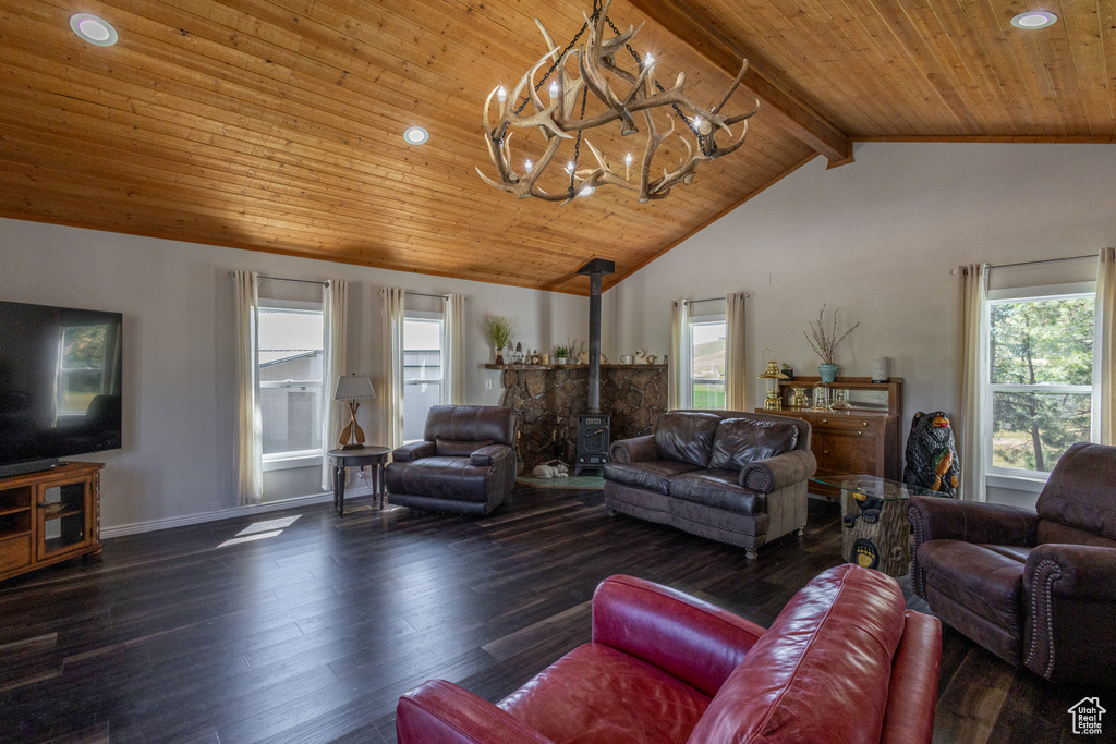 Living room with beamed ceiling, a wood stove, a wealth of natural light, and hardwood / wood-style flooring